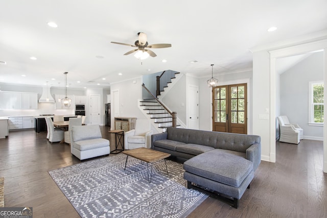 living room featuring ceiling fan with notable chandelier, dark hardwood / wood-style floors, and ornamental molding