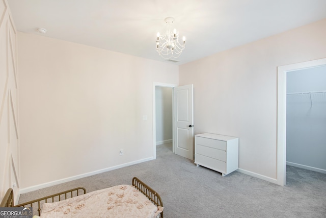 bedroom with a chandelier, a walk in closet, light colored carpet, and a closet