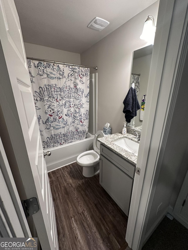 full bathroom featuring hardwood / wood-style floors, vanity, shower / bath combination with curtain, and toilet