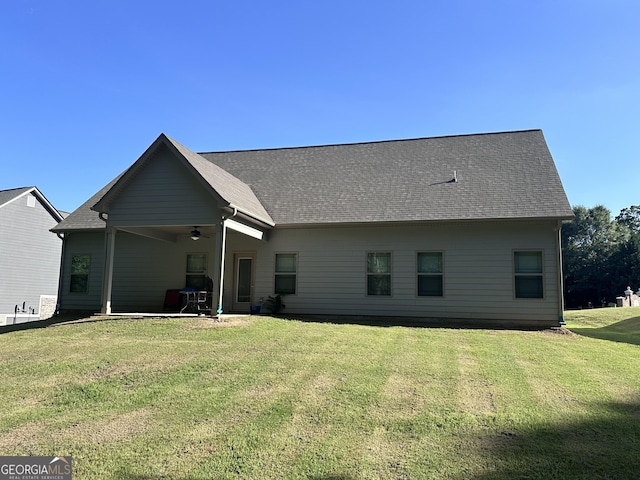 rear view of house featuring ceiling fan and a yard