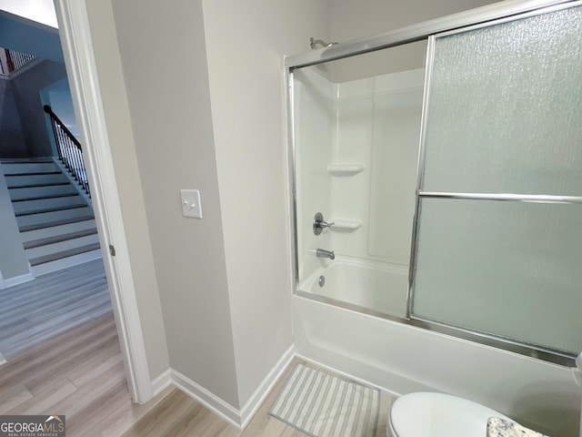 bathroom featuring wood-type flooring, toilet, and enclosed tub / shower combo