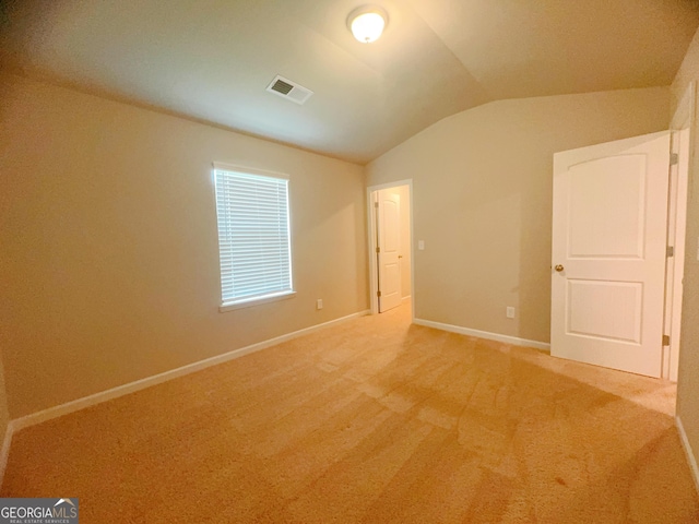 unfurnished room with carpet floors and vaulted ceiling