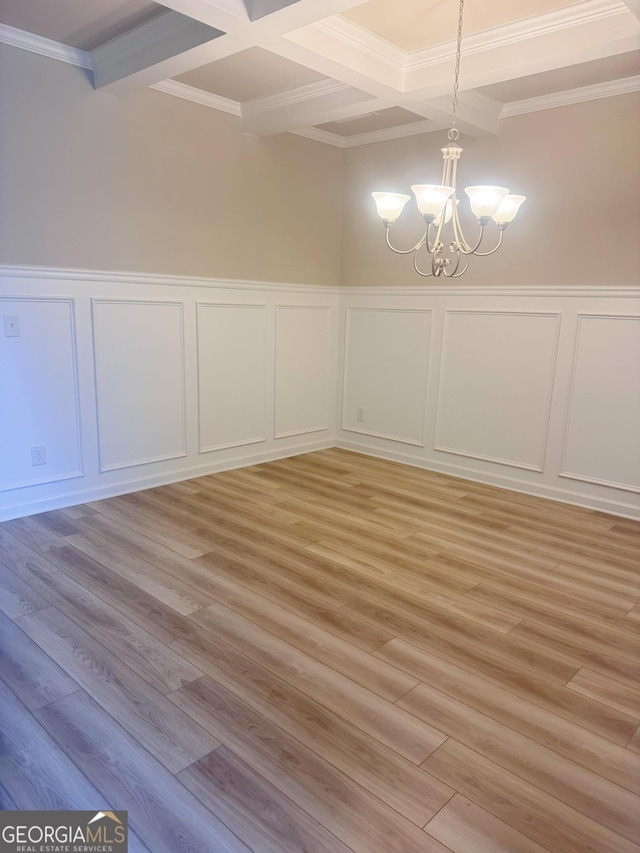 unfurnished dining area with coffered ceiling, an inviting chandelier, ornamental molding, beamed ceiling, and light hardwood / wood-style floors