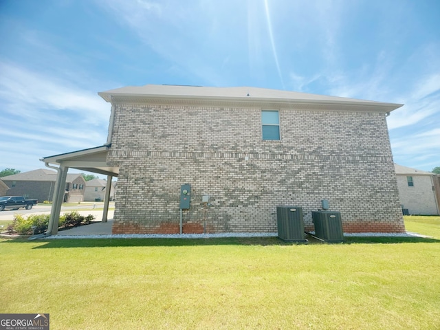 view of side of property with a lawn and central AC