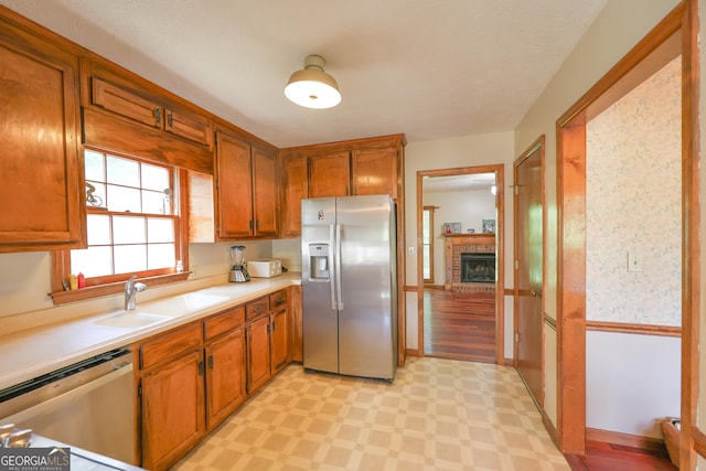 kitchen with sink, stainless steel appliances, and a brick fireplace