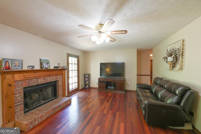 living room featuring a textured ceiling, ceiling fan, a fireplace, and dark wood-type flooring