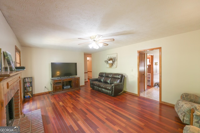 living room with a fireplace, ceiling fan, dark hardwood / wood-style flooring, and a textured ceiling