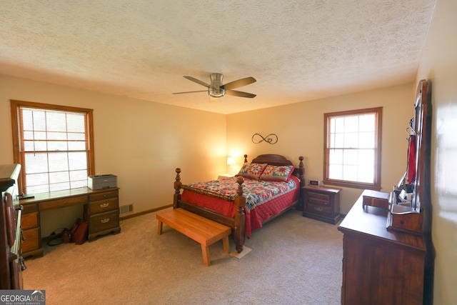 carpeted bedroom featuring multiple windows, ceiling fan, and a textured ceiling