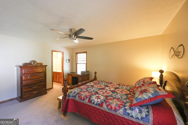 carpeted bedroom with a textured ceiling, ensuite bath, and ceiling fan