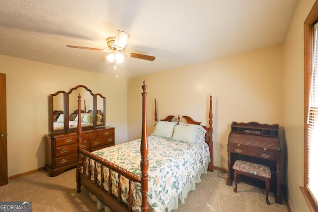 bedroom with ceiling fan, light colored carpet, and a textured ceiling