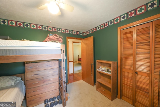 bedroom featuring a textured ceiling, ceiling fan, light carpet, and a closet