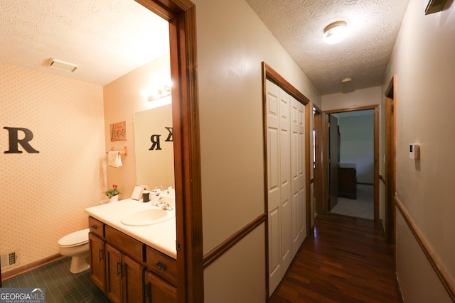 bathroom with vanity, wood-type flooring, a textured ceiling, and toilet