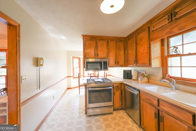 kitchen featuring a textured ceiling, stainless steel appliances, and sink