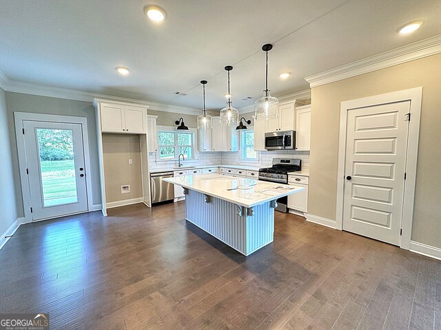 kitchen with stainless steel appliances, white cabinets, a wealth of natural light, and a center island