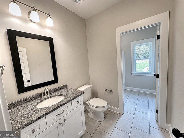 bathroom with a tub, vanity, toilet, and tile patterned floors