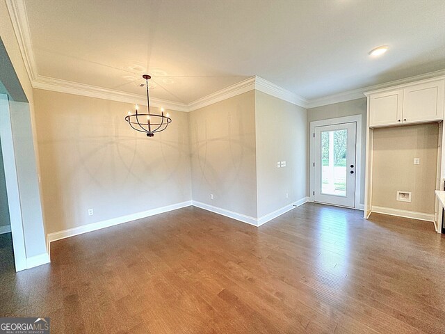 spare room with dark hardwood / wood-style floors, crown molding, and an inviting chandelier