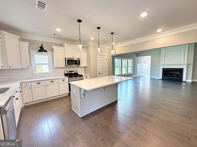 kitchen with white cabinets, hanging light fixtures, a center island, appliances with stainless steel finishes, and a breakfast bar