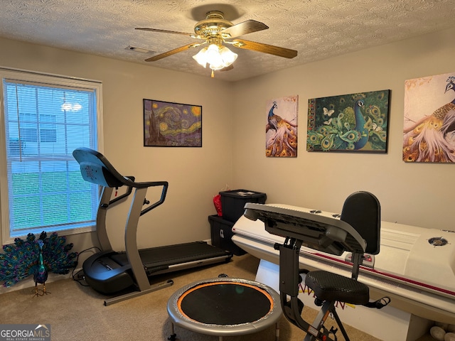 workout room featuring a textured ceiling, carpet flooring, and ceiling fan