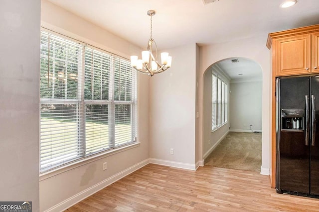 unfurnished dining area featuring light hardwood / wood-style floors, a wealth of natural light, and a chandelier