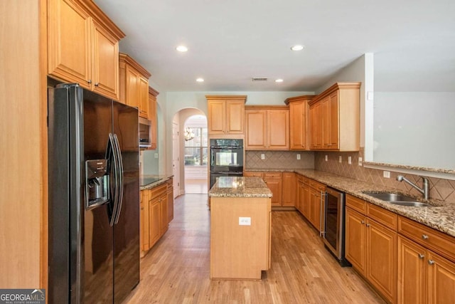 kitchen featuring light wood-type flooring, a center island, sink, and black appliances