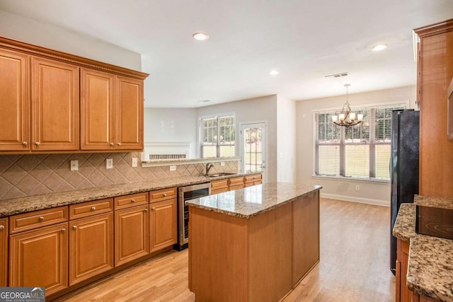 kitchen featuring a notable chandelier, decorative light fixtures, beverage cooler, and light hardwood / wood-style flooring