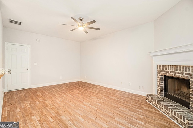 unfurnished living room featuring a brick fireplace, ceiling fan, and light hardwood / wood-style flooring