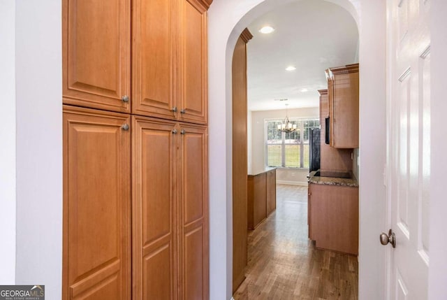 hallway featuring a chandelier and wood-type flooring