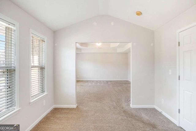 carpeted spare room with lofted ceiling