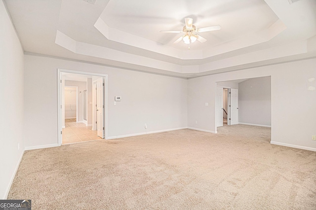 spare room featuring light carpet, ceiling fan, and a tray ceiling