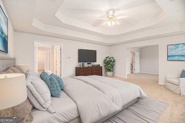 bedroom with a raised ceiling, connected bathroom, and light colored carpet