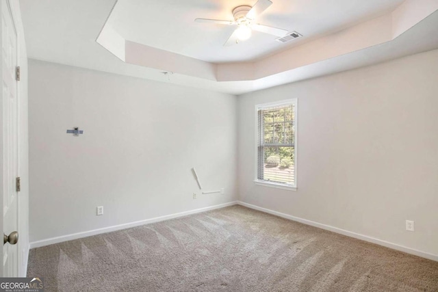 unfurnished room featuring carpet flooring, a tray ceiling, and ceiling fan