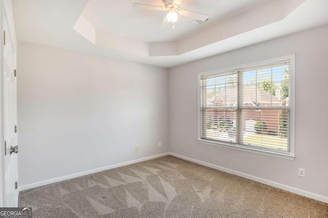 unfurnished room with ceiling fan, a raised ceiling, and carpet floors