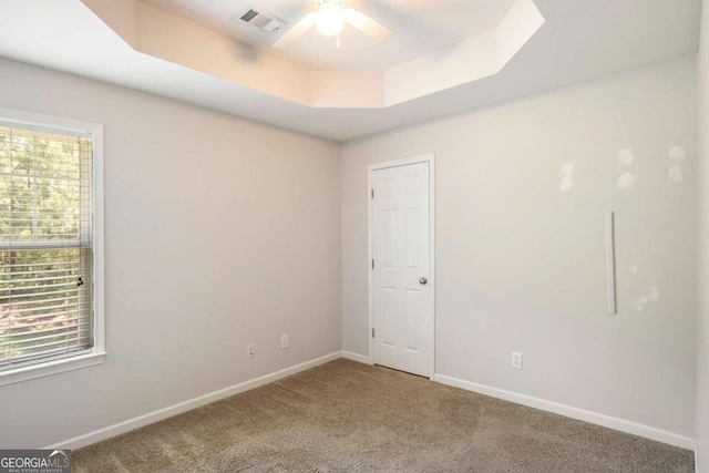 empty room featuring carpet flooring, ceiling fan, and a tray ceiling