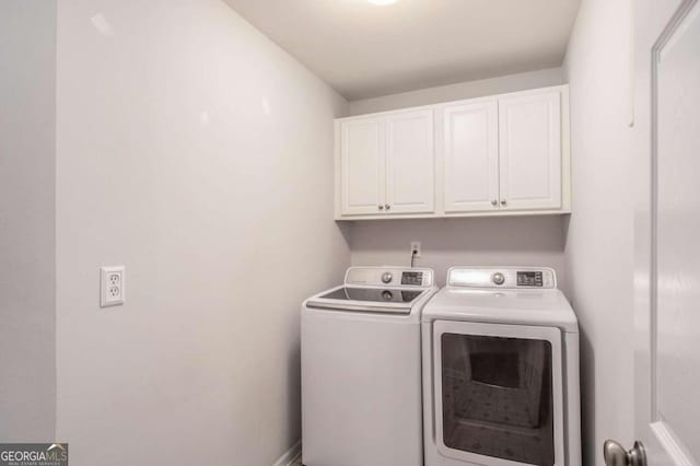 clothes washing area featuring cabinets and washer and dryer