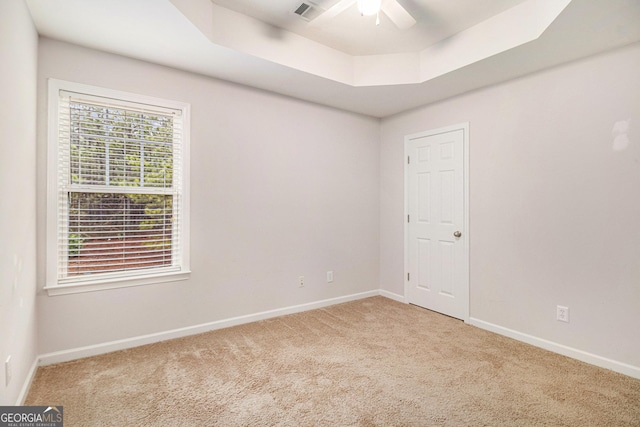 carpeted empty room with a tray ceiling and ceiling fan