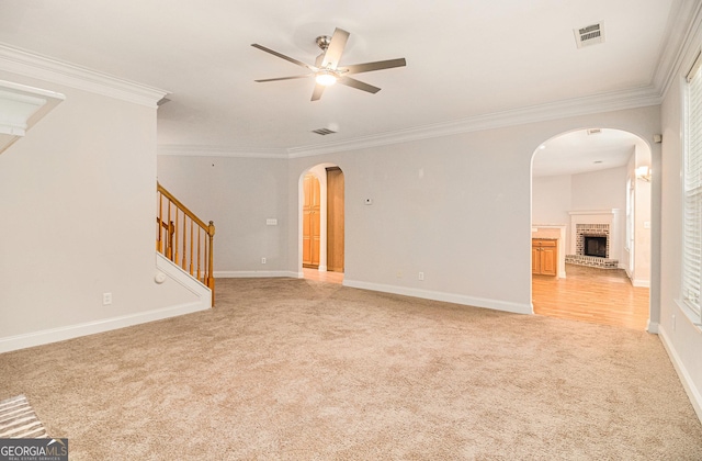 unfurnished living room with ornamental molding, light carpet, ceiling fan, and a fireplace