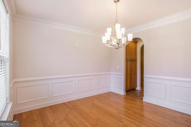 unfurnished room with wood-type flooring, a notable chandelier, and ornamental molding