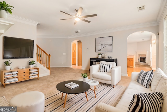 carpeted living room featuring ornamental molding and ceiling fan