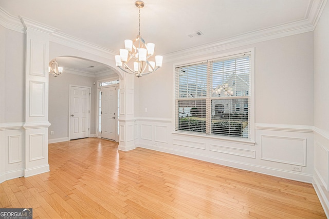 unfurnished dining area featuring hardwood / wood-style flooring, crown molding, and an inviting chandelier