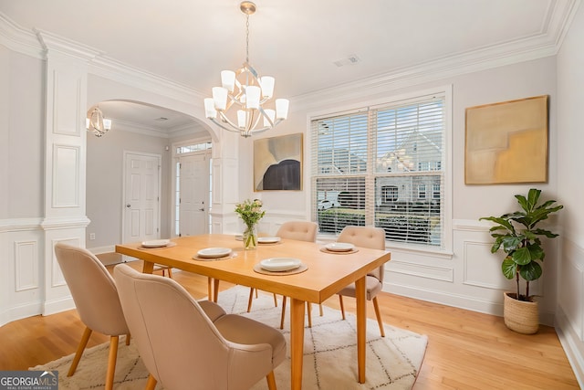 dining space with a notable chandelier, crown molding, and light wood-type flooring