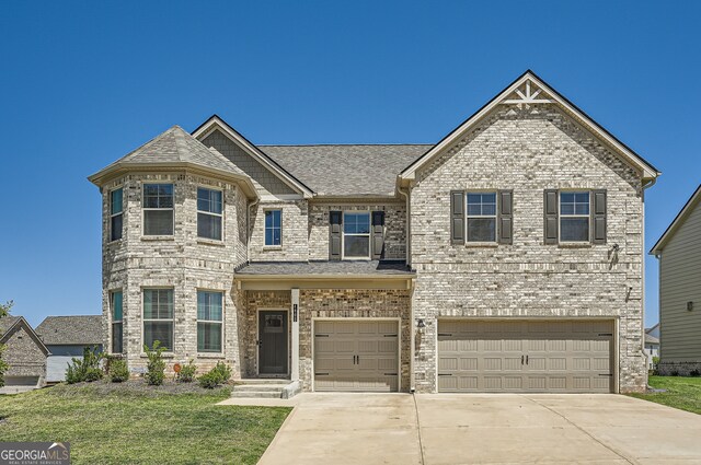 view of front of home with a shingled roof, concrete driveway, an attached garage, a front lawn, and brick siding