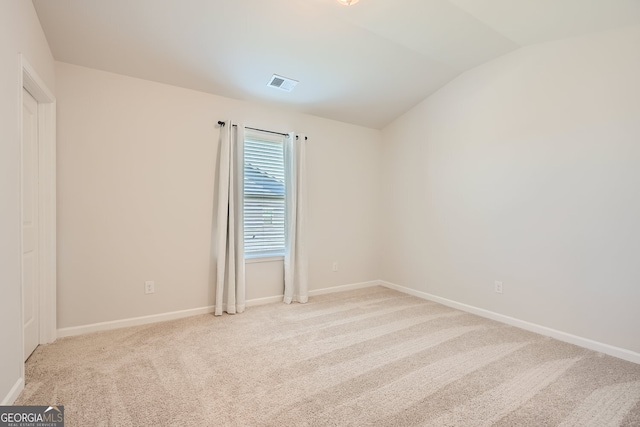 carpeted empty room featuring lofted ceiling