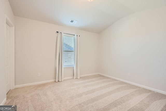 carpeted empty room with lofted ceiling, visible vents, and baseboards