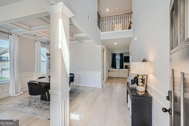 entryway with light wood-type flooring, beam ceiling, coffered ceiling, and decorative columns