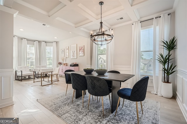 dining room with coffered ceiling, a healthy amount of sunlight, light wood-type flooring, and a chandelier