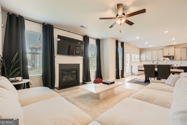 living room featuring recessed lighting, a large fireplace, visible vents, and light wood finished floors