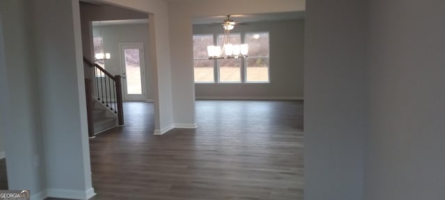 unfurnished dining area with ceiling fan with notable chandelier and dark wood-type flooring