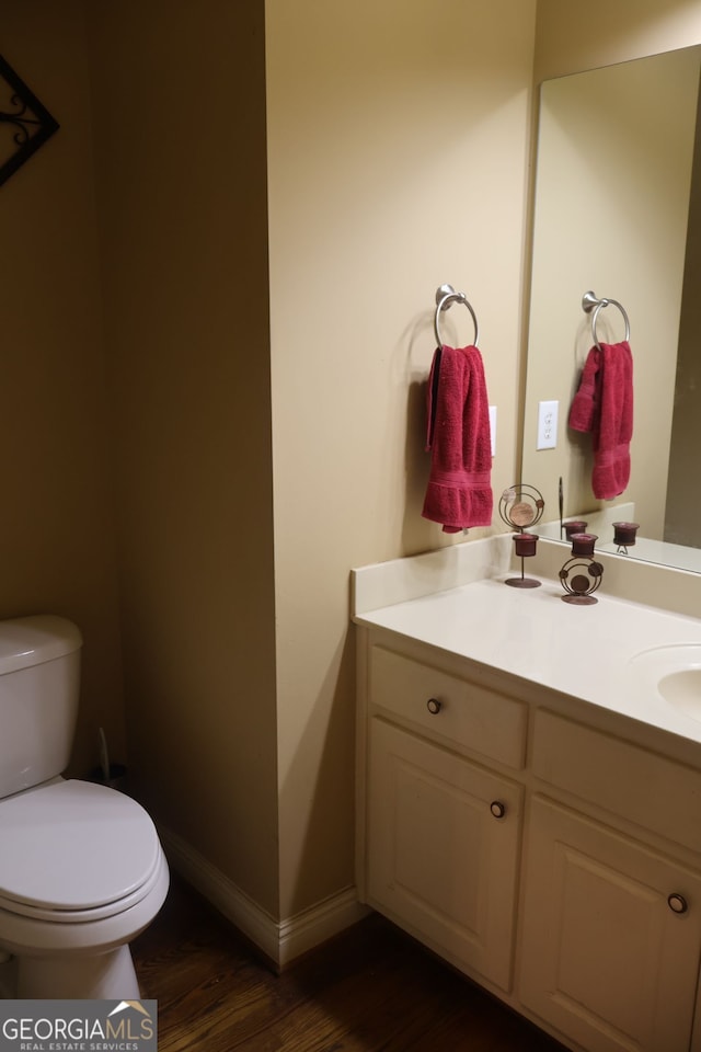 bathroom with toilet, hardwood / wood-style floors, and vanity