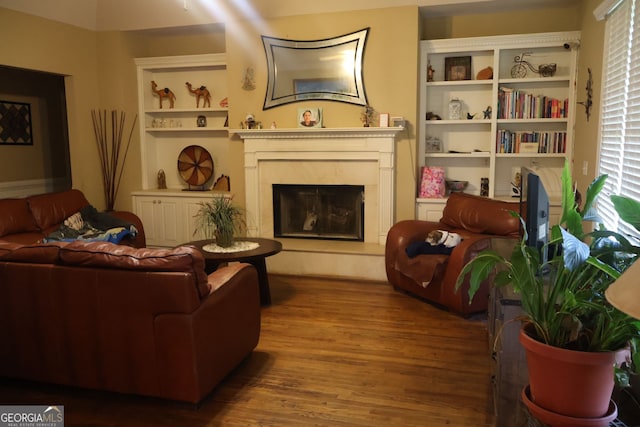 living room with a fireplace, built in shelves, and hardwood / wood-style floors