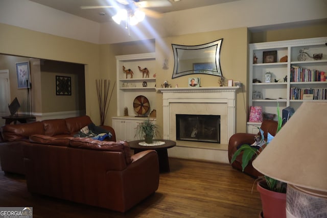 living room featuring a high end fireplace, built in features, dark hardwood / wood-style floors, and ceiling fan